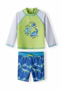 Rash guard à manches longues vert avec des accents bleus et des graphiques de requins, associé à un short de bain bleu orné de motifs de requins et d'un cordon de serrage.