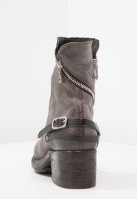 Graue Lederstiefeletten mit einem Riemen und einer Schnalle sowie einem seitlichen Reißverschluss, versehen mit einer strukturierten Oberfläche und einem massiven Holzabsatz.