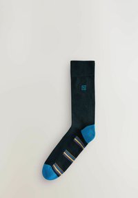 Calzino nero con punta e tallone blu. Presenta un motivo a strisce in viola, giallo e blu sulla pianta. Contiene un piccolo logo blu.