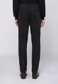 Černé kalhoty s rovnými nohavicemi, vybavené zadními kapsami a hladkou texturou. Minimalistický design bez viditelných vzorů nebo ozdob.