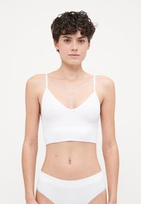 Bralette blanc à côtes avec fines bretelles, design en V et longueur cropped, assorti à des briefs blancs à côtes.