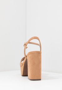 Hnědé semišové sandály na vysokém podpatku s širokým blokovým podpatkem, nastavitelným nártním páskem a otevřenou špičkou, s hladkým povrchem.
