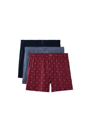 Trois paires de boxers pour homme en bleu marine, gris et rouge avec un petit motif de logo répétitif sur la paire rouge, empilées sur un fond blanc.