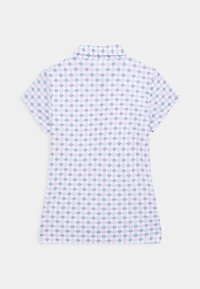 Kortärmad polo i mjukt tyg med en ljusblå bas och diamantmönster i rosa och svart, samt klassisk krage.