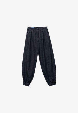 Ohlapne temno modre kavbojke iz jeansa z gubami na pasu, sprednjimi žepi in nabranimi robovi pri gležnjih.