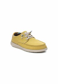 Zapatilla de lona amarilla con cordones beige y una superficie texturizada. Presenta una suela de goma beige y un forro interior con un patrón.
