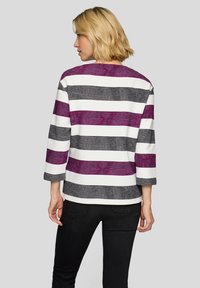 Gestreiftes Oberteil in lila, schwarz und weiß; Dreiviertelärmel; strukturierter Stoff; lockere Passform; runder Ausschnitt; einfarbiger Rücken.