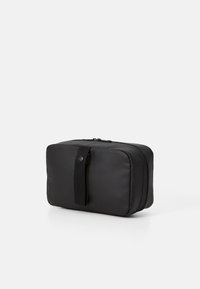Black rectangular cosmetic bag made of smooth material, featuring a top zipper closure and a fabric handle on one side.