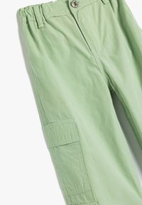 Lichtgroene cargobroek van een zachte stof, met een geplooide tailleband, knoopsluiting en zijzakdetails.