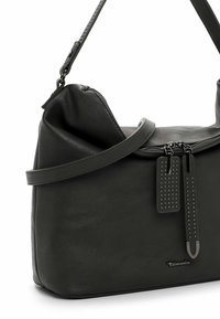 Borsa a tracolla in pelle verde scuro con design morbido, chiusura con zip e due etichette decorative con dettagli a borchie.