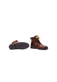 Botas de cuero marrón con una puntera texturizada y detalle de cremallera. Presentan una suela de goma con un diseño de dibujo para mayor tracción.
