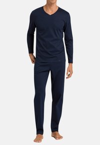 Tummansininen pitkähihaisen V-kaula-aukon paita ja yhteensopivat housut, jotka on valmistettu pehmeästä kankaasta. Mallissa on rento istuvuus ja minimaalinen muotoilu ilman kuvioita tai korostuksia.