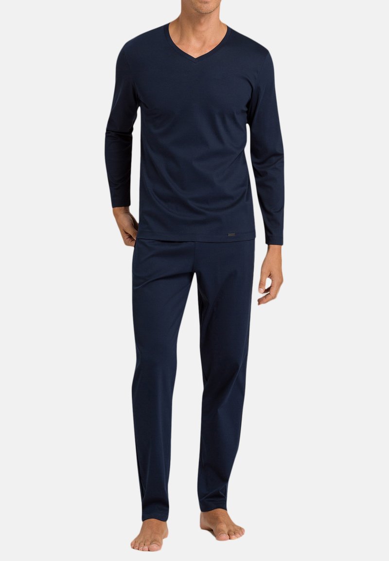 Tummansininen pitkähihaisen V-kaula-aukon paita ja yhteensopivat housut, jotka on valmistettu pehmeästä kankaasta. Mallissa on rento istuvuus ja minimaalinen muotoilu ilman kuvioita tai korostuksia.