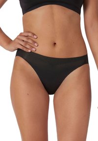 Zwarte bikini onderkant gemaakt van een gladde stof, met een lage taille en minimale bedekking. Subtiel geometrisch patroon langs de tailleband.