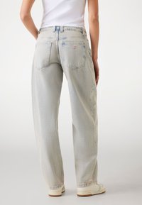 Ljusblå högmidjade jeans har en rak ben-design, subtila blekningar och bakfickor med en triangulär varumärkeslogga.