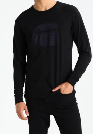 T-shirt noir à manches longues en tissu doux, avec un graphique ton sur ton violet prononcé sur le devant, de coupe régulière et avec un col rond.