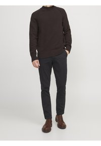 Mörkbrun stickad tröja med ribbat avslut, i kombination med svarta slim-fit byxor och bruna läder snörskor.