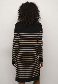 Strickkleid mit schwarzen und beigen horizontalen Streifen, langen Ärmeln, einer taillierten Silhouette und seitlichen Schlitzen am Saum.