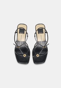 Μαύρα σανδάλια με λουράκια και τετράγωνη μύτη, λεπτά λουράκια, χρυσά διακοσμητικά καρφιά και μπεζ εσωτερικές σόλες με την επωνυμία "dolce vita".