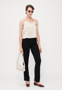 Lys beige sateng camisole, svarte tettsittende jeans, røde flate sko og en lys grå skulderveske. Tilbehøret inkluderer runde solbriller.