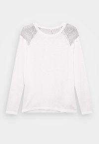 Camicia bianca a maniche lunghe con dettagli in pizzo sulle spalle, scollatura rotonda e orlo dritto, esposta su uno sfondo chiaro e semplice.