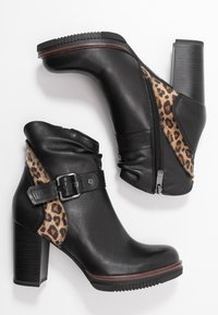 Mustat nahkaiset nilkkurit, joissa on leopardikuvioisia yksityiskohtia, vetoketjusuljenta ja paksu korko. Sisältää solkivarusteen sivussa.