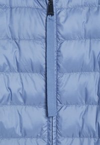 Jasnoniebieska kamizelka puchowa z poziomym pikowaniem, zamek błyskawiczny i pasujący uchwyt z materiału. Gładka, błyszcząca tekstura z izolacją.