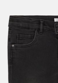 Vaqueros de mezclilla negra con una textura suave, que cuentan con un bolsillo delantero, un acento de metal en el bolsillo y costuras cosidas.