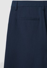 Marineblau maßgeschneiderte Hose mit einer glatten, strukturierten Oberfläche. Sie hat einen flachen Bund und eine einzelne Gesäßtasche mit gesteppten Details.