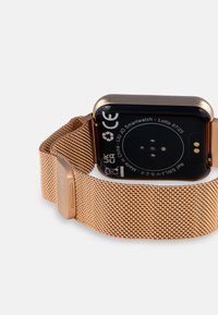 Smartwatch mit schwarzem Ziffernblatt und goldener Mesh-Armbanduhr. Auffällige goldene Hardware, glatte Oberfläche und sichtbare Sensorkontakte auf der Rückseite.
