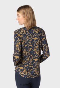 Langärmliges Oberteil mit einem floralen Muster in Marineblau auf goldenem Hintergrund, aus weichem, dehnbarem Stoff mit abgerundetem Saum.