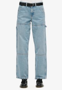 Pantalones cargo de denim azul claro con un corte relajado, que presentan grandes bolsillos, costuras de patchwork y un cinturón negro en la cintura.