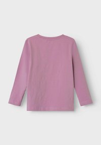 Camisa de manga larga en tela de color púrpura claro, con cuello redondo y dobladillo recto. Textura suave con detalles de costura visibles.