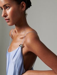 Φόρεμα από σατέν σε ανοιχτό γαλάζιο χρώμα με λεπτές τιράντες, που διαθέτει ασημένιο δαχτυλίδι στον ώμο. Ανοιχτή πλάτη και λεία υφή.