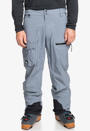 Grijze snowboardbroek met een ruime pasvorm, voorzien van meerdere zakken, ritsen en zwarte accenten. Gemaakt van een duurzaam, weersbestendig materiaal.