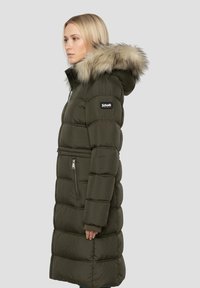 Lang olivengrøn dunjakke med hætte kantet med pels, quiltede sektioner, lynlåslommer og en figursyet talje.