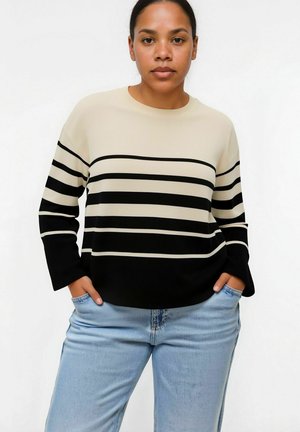 Maglione a righe nere e beige con maniche lunghe, texture a coste, scollatura rotonda, abbinato a jeans azzurri chiari.