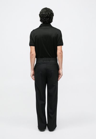 Μαύρο πόλο μπλουζάκι σε συνδυασμό με μαύρο παντελόνι με ραφινάτη γραμμή. Το πόλο έχει κοντά μανίκια και κλασικό γιακά. Τα παντελόνια έχουν σχεδίαση με ίσια γραμμή στο πόδι.