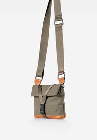 Khaki canvas crossbodytas met een klep, oranje leren accenten, verstelbare band en gespsluiting. Voorzien van een geperst logo.