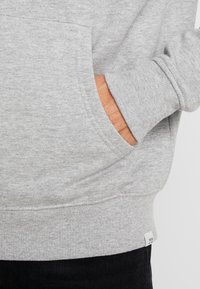 Grijze sweatshirt met een zachte textuur, een kangoeroezak, ribgebreide boorden en een merketiket aan de zoom. Eenvoudig ontwerp, klassieke pasvorm.