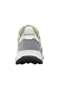 Vue arrière d'une basket Reebok grise et blanche avec une semelle noire et une doublure intérieure jaune.