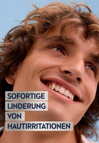 Smiling young man with tousled light brown hair, clear skin, and dental features; text overlay reads "Sofortige Linderung von Hautirritationen."