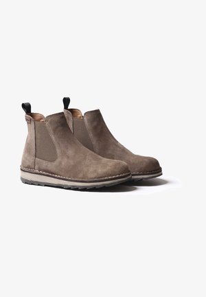 Paire de bottines Chelsea en daim taupe avec panneaux latéraux élastiques et languettes de tirage noires, présentant des semelles cousues sur un fond blanc.