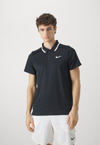 Juodas Nike trumpas rankovė polo marškinėliai su klasikinio tipo apykakle, baltais akcentais ir logotipu kairėje krūtinėje. Lygus audinys su prigludusia forma.