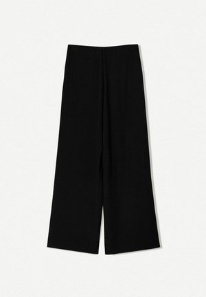 Pantalons larges noirs en tissu lisse, avec une taille haute, de coupe droite et sans embellissements ni motifs visibles.