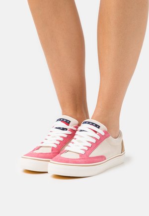 Sneaker rosa e crema con tomaia in suede, lacci bianchi e suola in gomma. Presenta una linguetta con marchio e un pannello texturizzato sul tallone.