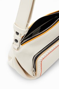 Borsa a spalla bianca in pelle con cerniere. Presenta un accento arancione e nero lungo le cuciture, una texture liscia e una forma strutturata.
