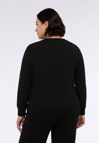 Felpa nera con maniche lunghe e scollo rotondo. Presenta un orlo e polsini a costine per un look aderente. Tessuto morbido e liscio.