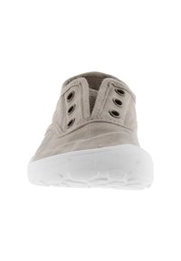 Zapato deslizante de color beige claro con parte superior de tela texturizada, suela de goma blanca y ojales circulares para ventilación.