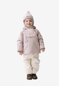 Casaco impermeável rosa claro com detalhe de estrela, calças de neve bege e botas castanhas. O chapéu é canelado e afunila no topo.